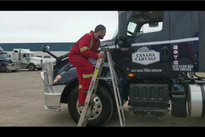 Employee is using a step ladder to reach the front window of a semi truck