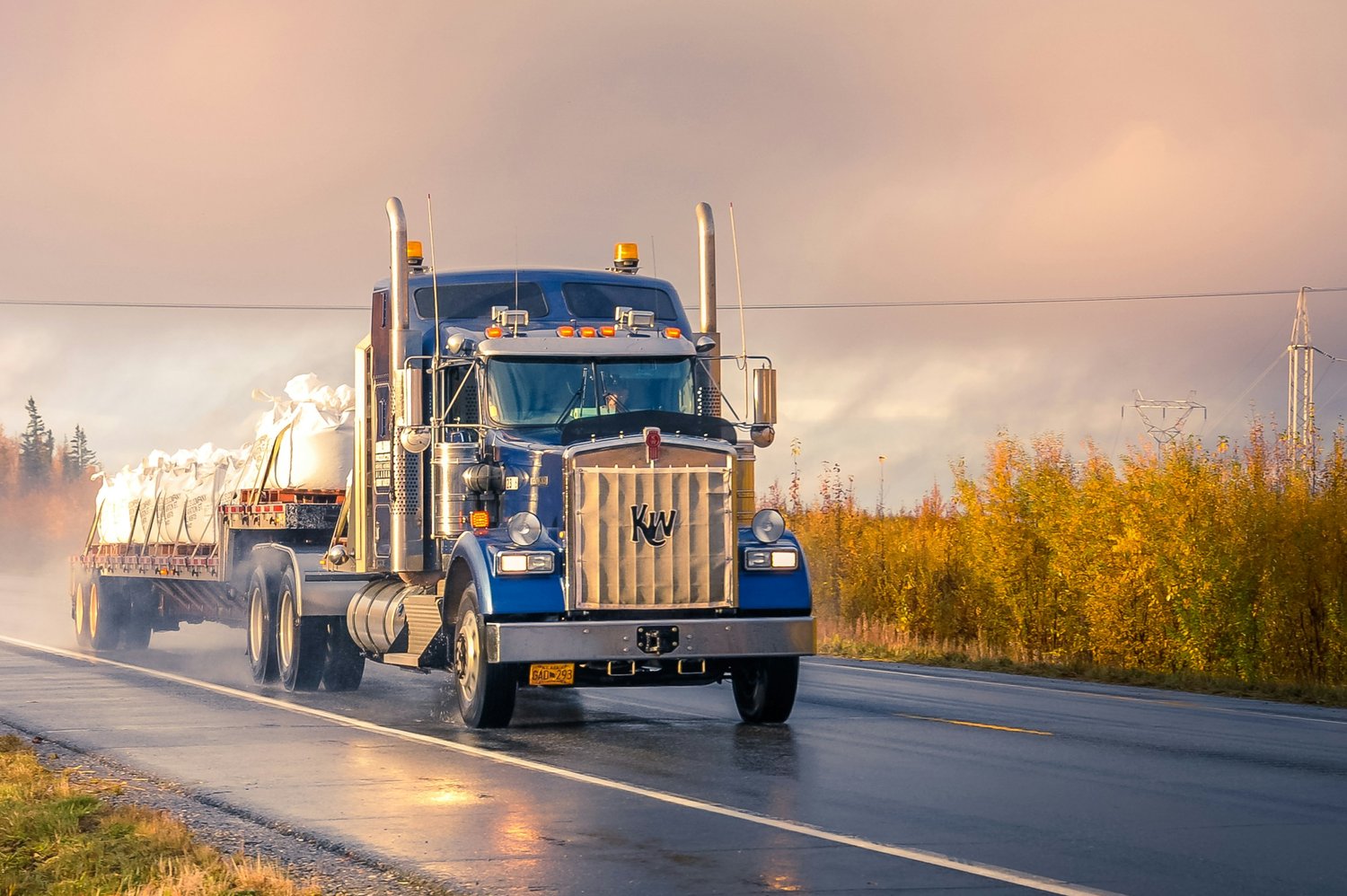 Semi truck driving down a wet highway