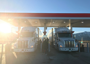 Two semi trucks parked at a gas station in Alberta