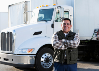Truck driver crossing his arms and smiling in front of white semi truck