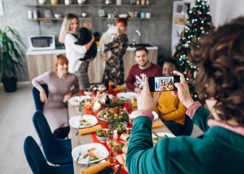 Person using a smartphone to take a photo of their colleagues at an office Christmas dinner party Person using a smartphone to take a photo of their colleagues at an office Christmas dinner party